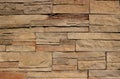 Stone cladding wall for rustic exterior, made of stacked natural brown rocks with irregular shapes Royalty Free Stock Photo