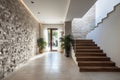 Stone cladding wall in spacious hallway with staircase. Luxury minimalist home interior design of modern entrance in villa Royalty Free Stock Photo