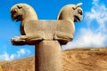 Stone column sculpture of a Griffin in Persepolis against a blue sky with clouds