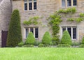 Stone cottage with topiary shrubs in front garden, Cotswolds, UK Royalty Free Stock Photo
