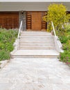 A stone covered corridor to house entrance stairs and natural wood door.