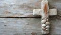 Stone cross with feather and pebbles on wood backdrop, palm sunday greetings concept