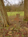 Natural burial ground in nature with stone cross in between tree trunks Royalty Free Stock Photo