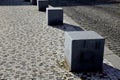 Stone cubes barriers as protection of a nice lawn cube cubes on a paved sidewalk platform of a tram protected from the entry of ca Royalty Free Stock Photo