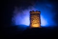 Stone defence tower at night. Medieval castle miniature with toned foggy backlight. Creative table decoration