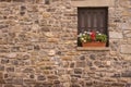 Stone facade with window detail decorated with red flowers