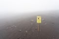 stone fall warning sign on a foggy day on the pedestrian path to the top of the mount vesuvio volcano.  Naples, Italy. Royalty Free Stock Photo