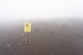 stone fall warning sign on a foggy day on the pedestrian path to the top of the mount vesuvio volcano.  Naples, Italy. Royalty Free Stock Photo