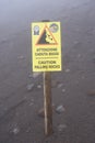 stone fall warning sign on a foggy day on the pedestrian path to the top of the mount vesuvio volcano.  Naples, Italy. Royalty Free Stock Photo