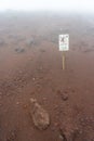 stone fall warning sign on a foggy day on the pedestrian path to the top of the mount vesuvio volcano. Naples, Italy.