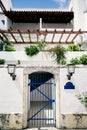 Stone fence with lattice gates near the house with a large balcony and greenery