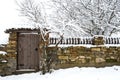 Stone fence and old rustic wooden door covered with snow Royalty Free Stock Photo