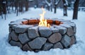 A stone fire pit burning with bright flames in a snowy outdoor setting Royalty Free Stock Photo