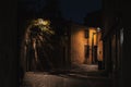 Stone floor of an old street between dark ancient buildings with lights at night