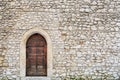 Stone fortress castle wall of a medieval castle, an old wooden closed arcade door with iron rivets.