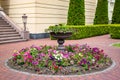 Stone fountain flower bed in backyard with blooming petunias.