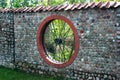 Stone garden fence with round window shaped like a wheel Royalty Free Stock Photo