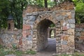 Stone gate in the archway vista and a brick wall with a miniature tower in the style of a medieval castle in park Royalty Free Stock Photo