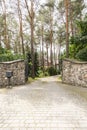 Stone gate and driveway into forest with residence. Real photo