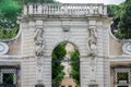 Stone gate to enter the park with columns in the form of a human woman with a coat of arms and believing in the capital of Italy,