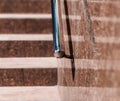 Stone granite stairs steps background with metallic aluminium handle. Red brown modern stairs