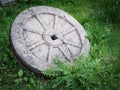 Stone granite wheel with rusted metal rim isolated on green grass. Royalty Free Stock Photo