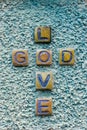 Stone graved text crossing of GOD LOVE on rough texture wall, vertical shot