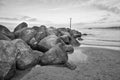 Stone groyne juts out into the water off the coast in Denmark. Black and white shot Royalty Free Stock Photo