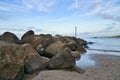 Stone groyne juts out into the water off the coast in Denmark. Sunny day. Landscape Royalty Free Stock Photo