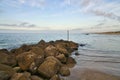 Stone groyne juts out into the water off the coast in Denmark. Sunny day. Landscape Royalty Free Stock Photo