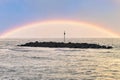 Stone groynes, breakwaters in the water off the coast in Denmark. Rainbow Royalty Free Stock Photo