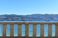 Stone handrail in a beach promenade background. Turqouise water, boats in a bay, blue sky, sunny day. Galicia, Rias Baixas, Spain. Royalty Free Stock Photo