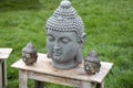 Stone heads of Buddha on a wooden table in the garden