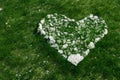 Heart sign laid out from white rough stones on grass.