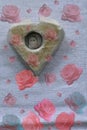 Stone of heart with the image of the Virgin Mary on a white canvas with decorative roses.