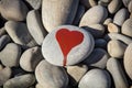 stone heart painted with a red paint marker on the pebble as a gift for Saint Valentine day on the pebble background Royalty Free Stock Photo