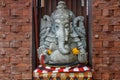 Stone Hindu Ganesha statue in sarong, decorated with Marigold flowers. Bali, Indonesia.