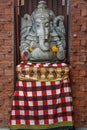 Stone Hindu Ganesha statue in sarong, decorated with Marigold flowers. Bali, Indonesia.