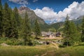 Stone house at Alpe Devero, Piedmont with trees and alps in the background Royalty Free Stock Photo