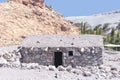 Stone house in desert oasis next to sand dunes