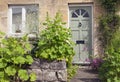 Stone house with pastel green doors and cottage flowers in front . Royalty Free Stock Photo