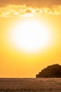 Stone hut in a golden cereal field with the sun behind it on a summer evening