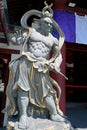 Stone image of a fierce and wrathful guardian of the Buddha, Narayana, at left entrance of a Buddhist temple in East Asia