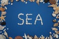 Stone Inscription, text, word: SEA over Blue Background. Shells Frame. Nautical and Marinne Concept. Royalty Free Stock Photo