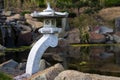 Stone lantern and rocks at a pond, garden landscape design in Japanese style Royalty Free Stock Photo