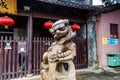A stone lion statue in front of wooden historic buildings of city temple in Zhujiajiao in a rainy day, an ancient water town in