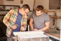 Stone Mason With Apprentice At Work On Carving In Studio