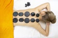Stone massage Top view of beautiful young woman lying on front with spa stones on her back. Beauty treatment concept Royalty Free Stock Photo