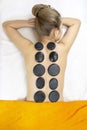 Stone massage treatment. Top view of beautiful young woman lying on front with spa stones on her back. Beauty treatment concept. Royalty Free Stock Photo