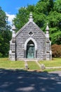 Stone mausoleum with Christian symbols and wrought-iron gate with trees in the background, at Sleepy Hollow Cemetary in Upstate